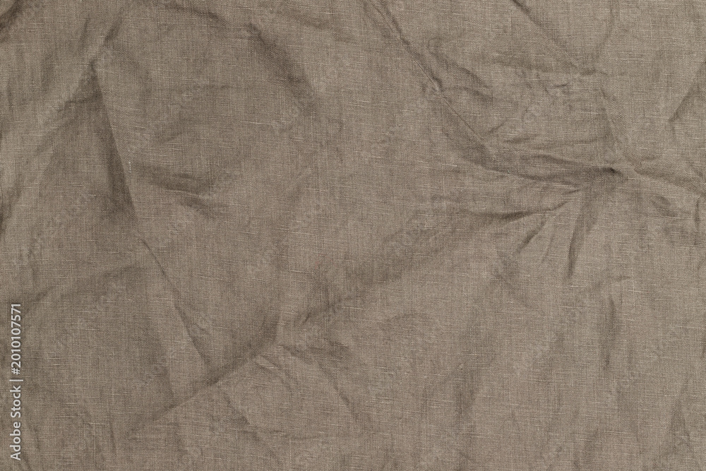 Fototapeta premium Light brown fabric with wrinkles is arranged on a flat surface in a well-lit room during the day