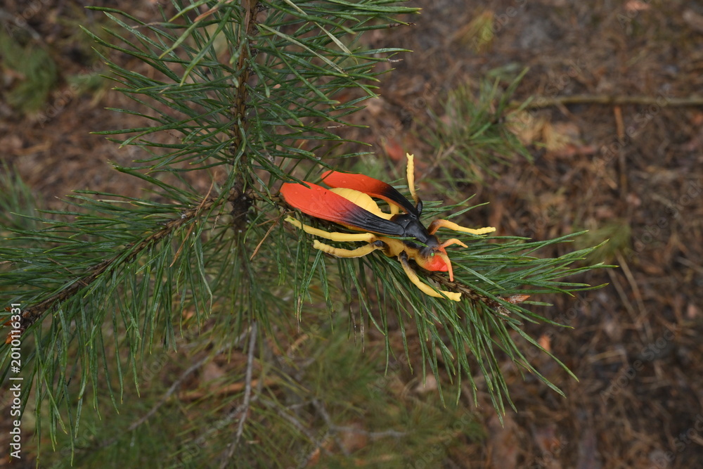 Obraz premium Toy hornet replica resting on green pine tree needles simulating a nature in wildlife scene