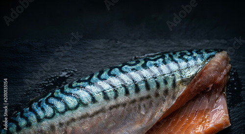 Close-up of a vividly colored, patterned mackerel fish resting on a dark surface showcasing intricate scales and a vibrant,