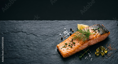 Freshly Pan-Seared Salmon Fillet Garnished with Lemon and Fresh Herbs on Slate Plate