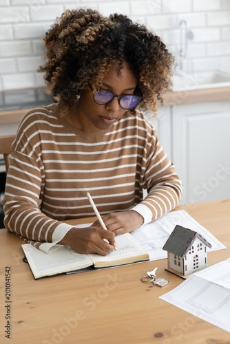 Photos female architect designer is working, taking notes in notebook is mock up of house on table