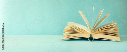 Fotografie opened book on smooth green blue background,education,knowledge,reading concept