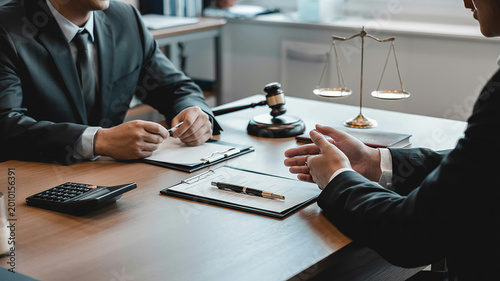 Two businessmen in suits discussing documents at a desk with legal symbols lawyers justice