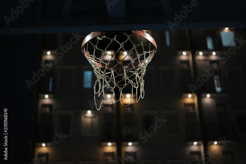 Night basketball hoop with blurred city apartment background