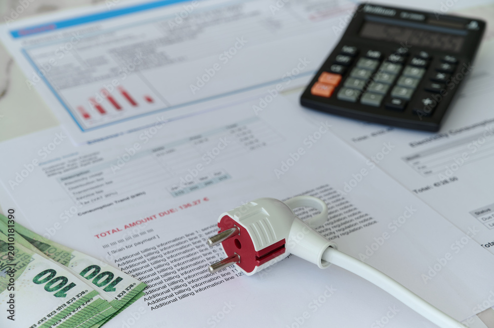Fototapeta premium Documents show electricity bills with a calculator and cash on the table in a home office environment.