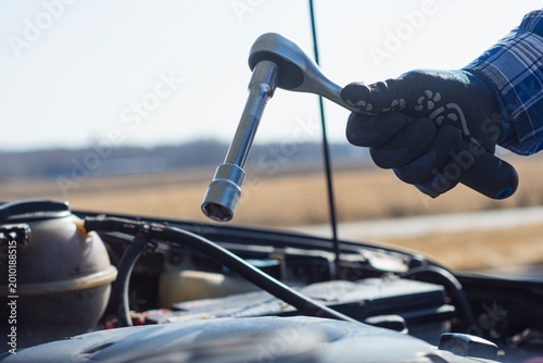 Foto Gloved hand holding a socket wrench with extension over an open car engine bay