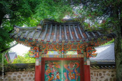 Mysterious light glowing through a traditional Korean temple gate, portal to another world (Ancient Buddhist temple door with colorful guardian paintings and ethereal light at Bulguksa, Gyeongju)