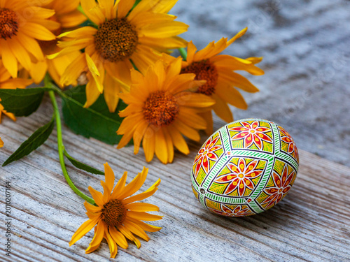 Hand-Painted Ukrainian Easter Egg Pysanka with Yellow Daisies on Wooden Surface