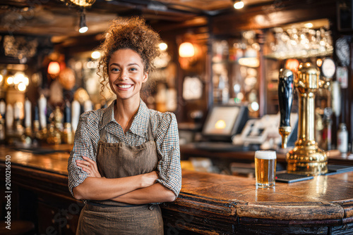 A smiling bartender stands confidently behind the bar in a cozy pub with wooden decor and a draft beer on the counter.