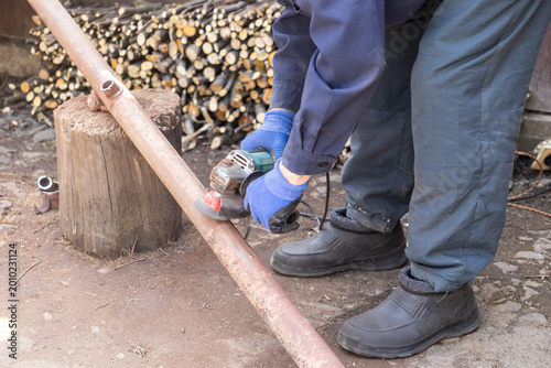 Fotografie An industrial worker uses a powerful electric angle grinder to smooth and polish