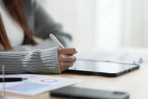 Obraz na plátne Focused woman writing on tablet screen with digital pen reviewing business docum