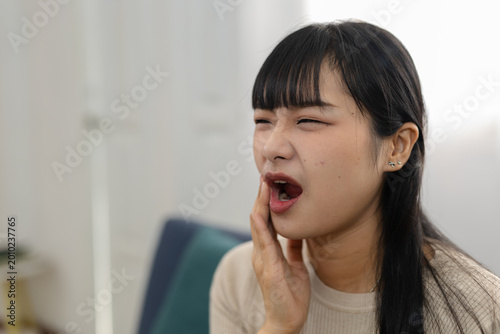 Fotografie Young asian woman holding jaw with open mouth suffering severe pain and terrible