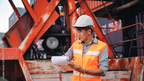 Industrial worker safety helmet safety vest clipboard cargo container construction site outdoor inspection engineer logistics worker focused industrial worker wearing safety helmet and safety vest