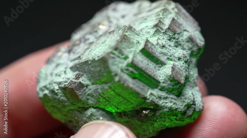 Macro high angle shot of a raw, crystalline emerald-green mineral rock with a rough and rugged textured surface.