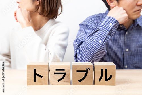 「トラブル」と書かれたブロックと喧嘩をする夫婦