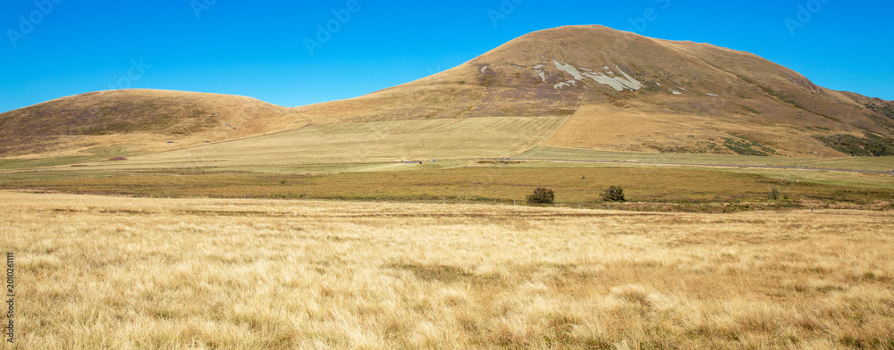 Obraz premium panoramic wide angle view of dry golden hills and mountains under a clear blue sky in autumn