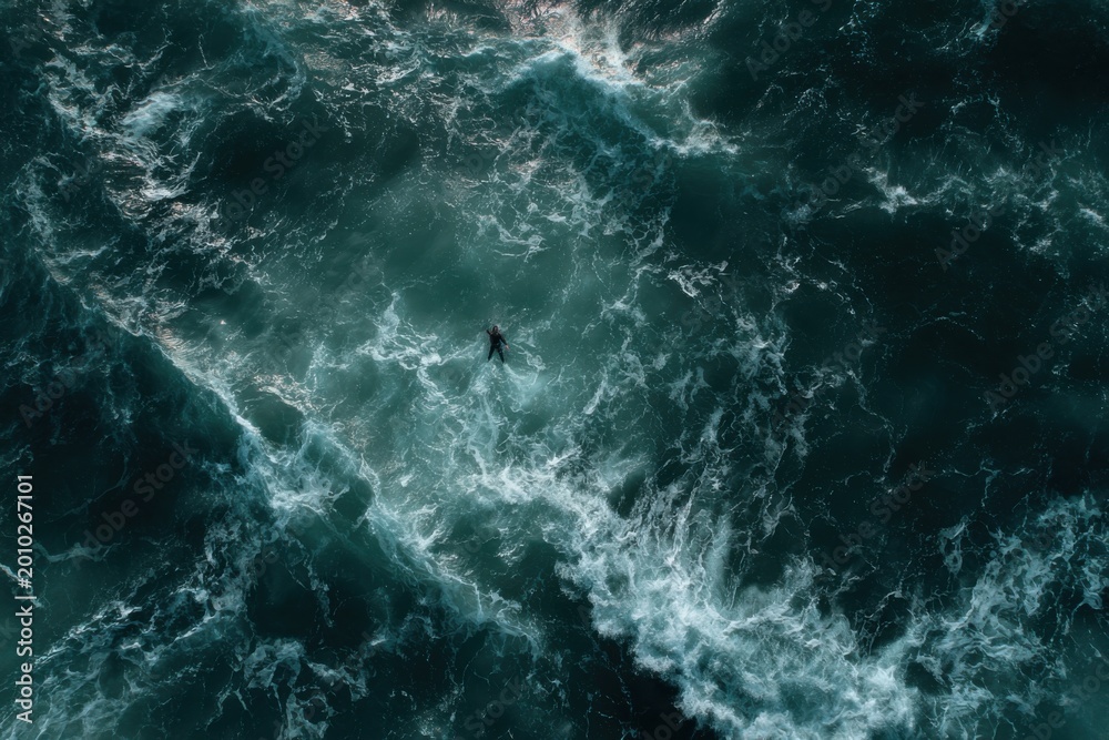 Fototapeta premium Aerial View of a Lone Person Floating in Turbulent Ocean Waves.