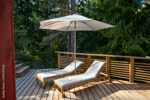 Foto luxury outdoor lounge chairs on wooden terrace with umbrella in forest retreat r