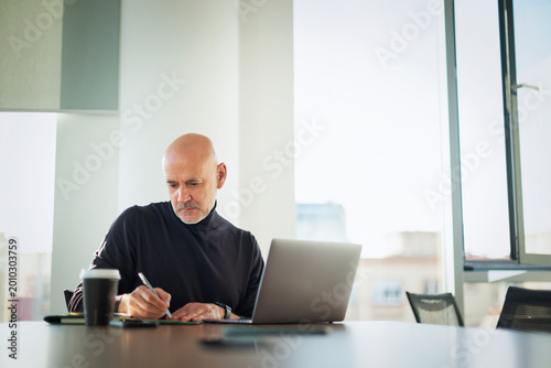 Mid-aged businessman sitting in a meeting room table and working on laptop