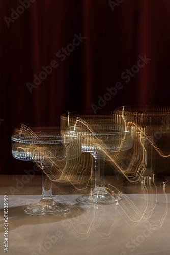 Elegant Ribbed Glass with Champagne on a Red Velvet Background. Motion Blur