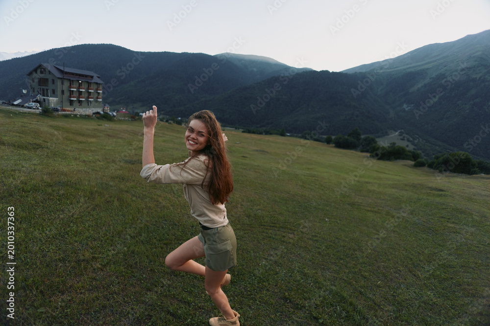 Naklejka premium Happy woman outdoors posing on green grass field with mountains in background casual outfit natural light smiling joyful lifestyle summer day