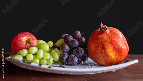 Billede på lærred Apple grapes, pomegranate on the plate