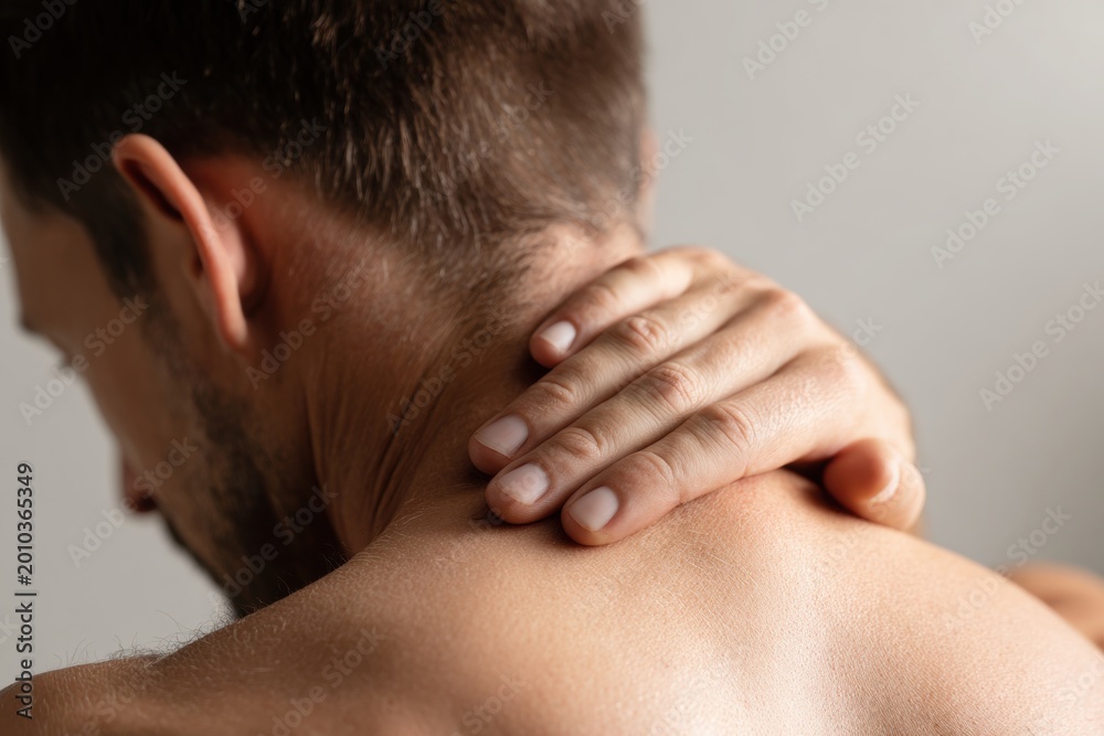 Fototapeta premium Person back view touching neck with hand feeling pain