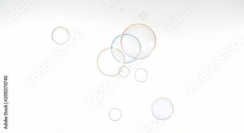 Soap bubbles float gently against a clean white background creating a sense of calm and serenity with their transparent and colorful forms