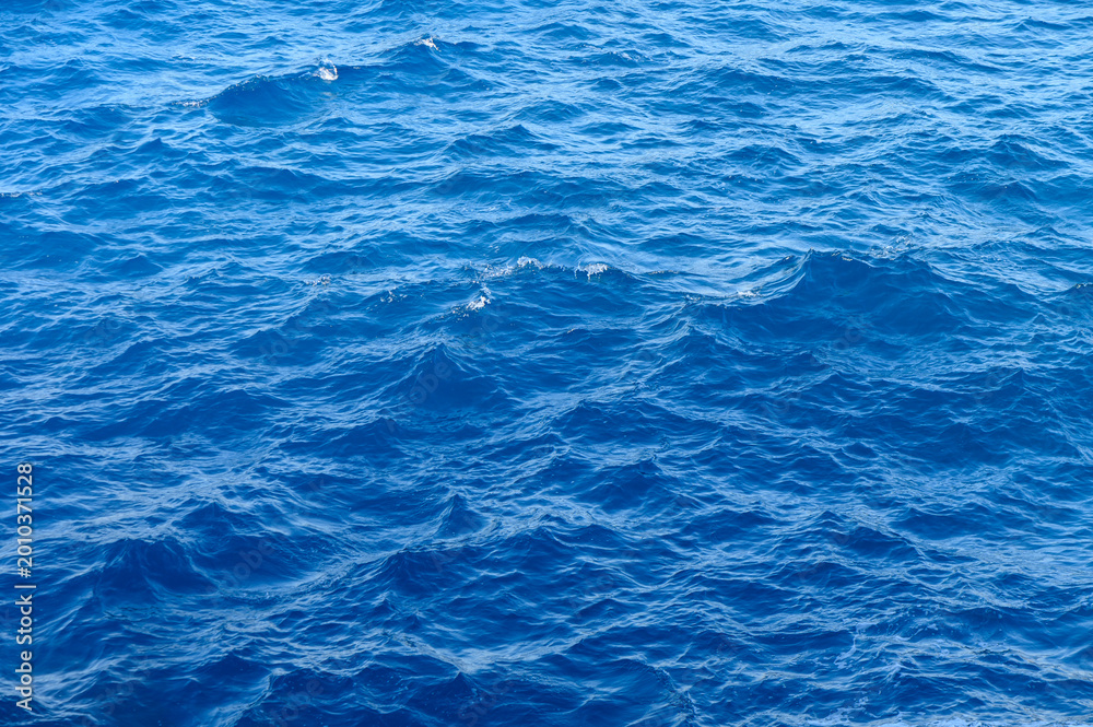 Obraz premium Vibrant blue sea dances under the sun at a serene coastal horizon, inviting tranquility and exploration.
