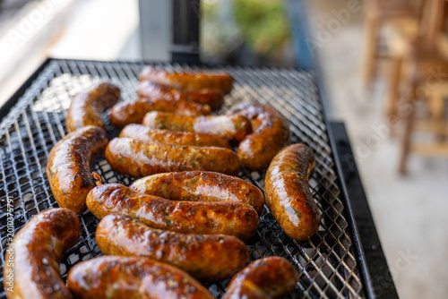 Foto Delicious hot pork sausage cooking on metal barbecue grill over fire