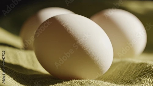 Three White Chicken Eggs Macro View With Cinematic Side Lighting On Green Textured Fabric