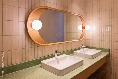 Wood-framed mirror in bathroom with lights and sink with silver faucet and socket.