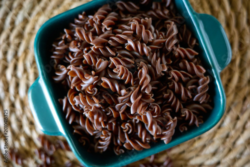 Tableau sur toile Freshly cooked chocolate pasta in a blue bowl placed on a woven mat with some pa