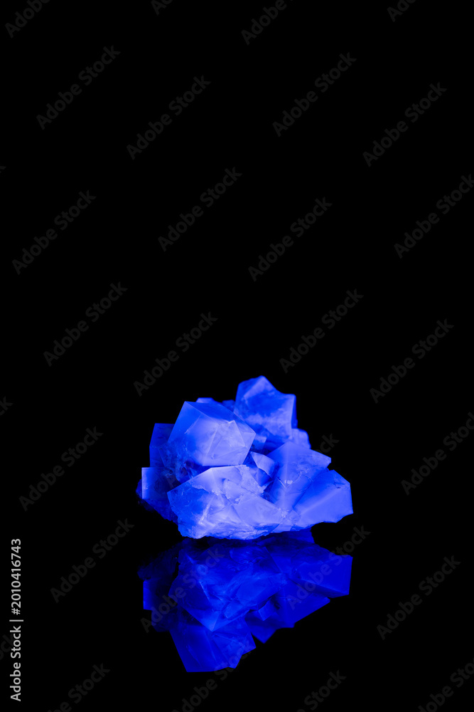 Naklejka premium Fluorescent fluorite crystal under UV light on black background with reflection