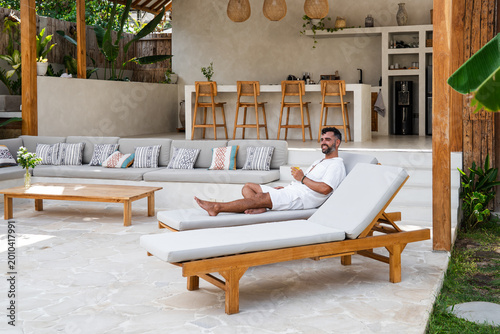 Photos Man enjoying leisure time on a sun lounger at a modern outdoor patio