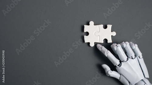 Εκτύπωση καμβά Close up of a white robotic hand touching two interlocking puzzle pieces on a grey background representing AI problem solving and integration