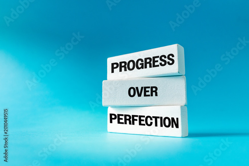 Progress Over Perfection message on white wooden blocks over blue background. Motivational concept for personal growth and business
