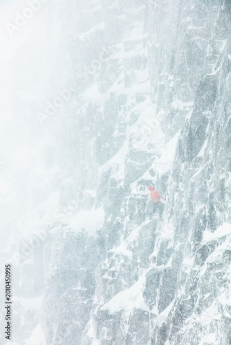Fotografija climber ascending in whiteout snowstorm on exposed alpine face, extreme winter,