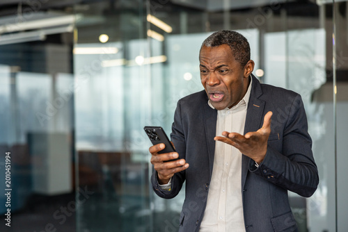 Canvas-taulu Mature executive showing frustration while browsing unpleasant content on his mo