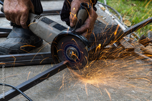 Foto Metalworking with Angle Grinder Sparks Flying Outdoors
