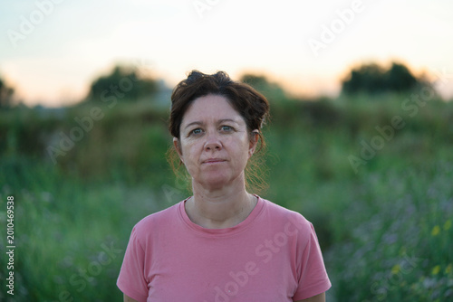 Portrait of a woman with a serious face, while taking an afternoon stroll in the countryside
