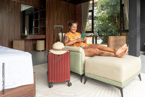 Fotografie Woman relaxing in hotel room using smartphone on vacation