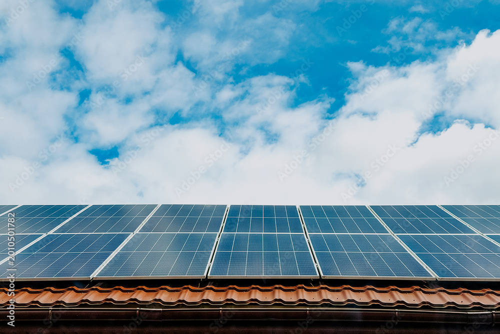 Fototapeta premium Solar panels on a tiled roof under a cloudy sky
