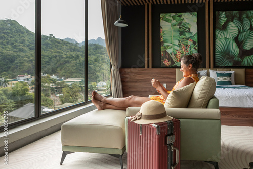 Woman relaxing in luxury hotel room watching mountain view