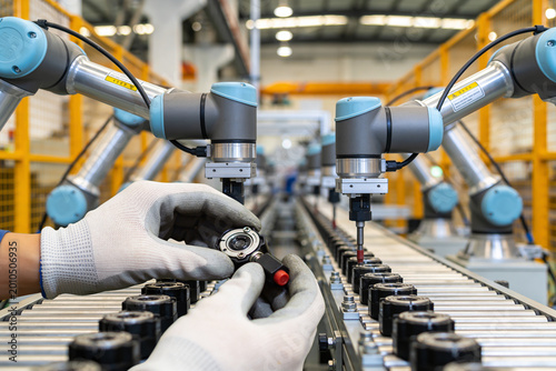 Fotografie Automated assembly line with robotic arms and human worker inspecting parts
