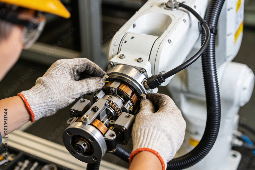 Fototapeta premium Technician in safety helmet and gloves meticulously assembling a robotic arm component