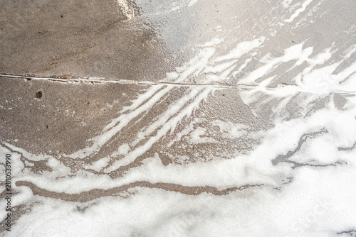 Foto White foam covers ground with vertical flowing streaks creating natural abstract