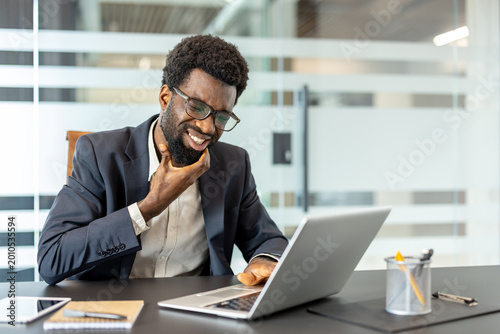 Fotografie Man in an office experiencing an uncomfortable toothache or gum pain while tryin