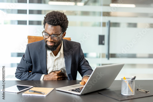 Photography Professional african ethnic man experiencing abdominal pain while working on a l