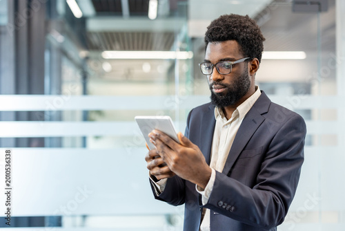 Foto Young professional man with beard and glasses studying data on a digital tablet,